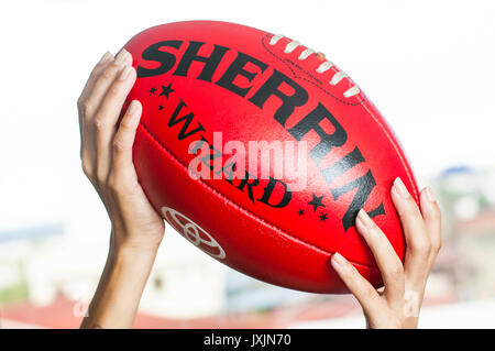 Young Asian woman holding Australian rules football AFL Banque D'Images