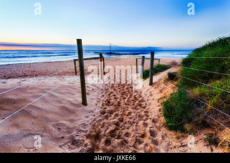 Se félicite de la plage de sable doux et à Mona Vale beach à Sydney au lever du soleil. Les piscines d'eau de mer lointaine prêt pour les nageurs. Banque D'Images