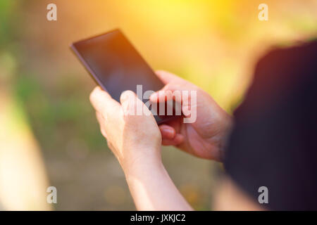 Personne de sexe féminin en utilisant smartphone outdoors, saisie de texte Message avec son pouce, selective focus Banque D'Images