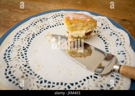 La dernière tranche de confiture et de crème gâteau éponge sur un papier dolly Banque D'Images