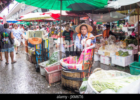 Femme porter, clients et vendeurs sur les marchés traditionnels de Khlong Toei, Bangkok, Thaïlande Banque D'Images