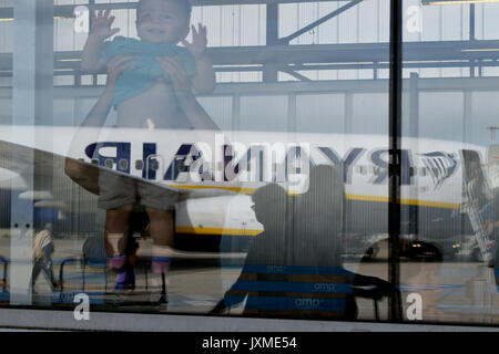 Un enfant est maintenu jusqu'à voir un avion de Ryanair en tant que passagers débarquer à l'aéroport Marseille Provence. Vu à travers la fenêtre de terminal Banque D'Images