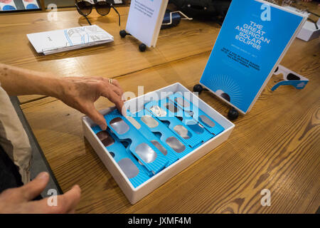 Des clients à la protection des yeux Lunettes de protection eclipse gratuit fourni par l'entreprise de lunetterie Warby Parker dans leur magasin dans le Meatpacking District à New York, le vendredi 12 août 2017. Le 21 août une éclipse totale va traverser les États-Unis à New York, obtenant environ 70 pour cent de la totalité. (© Richard B. Levine) Banque D'Images