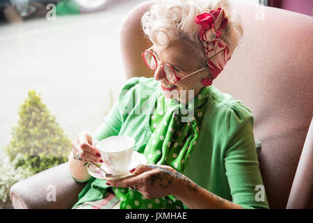 Heureux quirky vintage mature woman holding tasse et soucoupe à thé Banque D'Images