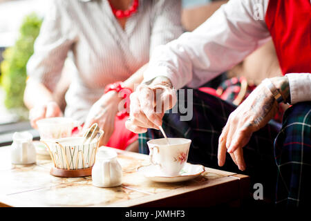 Close up of hands of senior man en remuant dans vintage tea rooms Banque D'Images