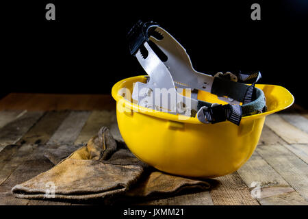 Casque jaune et gants de soudeur. Fond noir et de la vieille table en bois. Banque D'Images