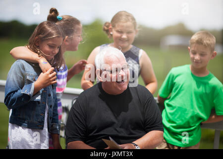 Grand-père entouré de petits-enfants lui donnant carte de souhaits Banque D'Images