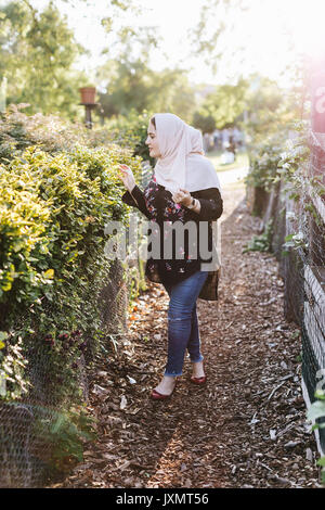 Jeune femme portant le hijab en admirant les plantes Banque D'Images