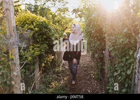 Jeune femme portant le hijab en admirant les plantes Banque D'Images