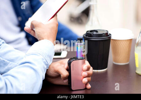 Portrait of man holding smartphone et vape Banque D'Images