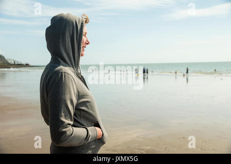 Woman on beach en haut à capuchon, Folkestone, Royaume-Uni Banque D'Images