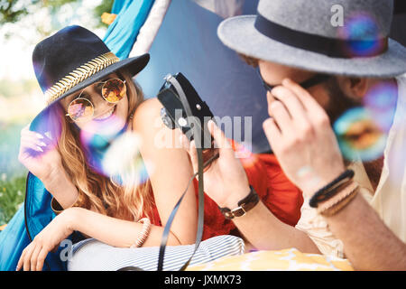 Boho jeune couple lying in tent looking at camera au festival Banque D'Images