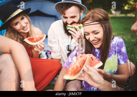 Les jeunes adultes boho friends eating tranches de melon au festival Banque D'Images