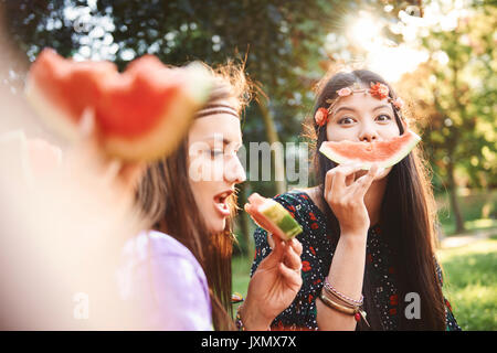 Les jeunes femmes boho faisant sourire avec tranche de melon au festival Banque D'Images