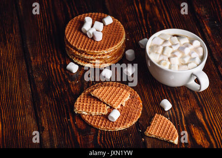 Avec une rupture Stroopwafel avec blanc tasse de cacao avec de la guimauve et Waffle Pile. Copie de l'espace sur la gauche. Banque D'Images