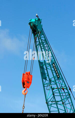 Grue mécanique vert avec crochet orange vif et système de poulies contre le ciel bleu Banque D'Images