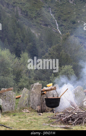La semoule de polenta italienne (bouillie) par cuisson lente sur la flamme dans un chaudron sur un feu de charbon de bois et au cours d'un repas rural dans une forêt Banque D'Images
