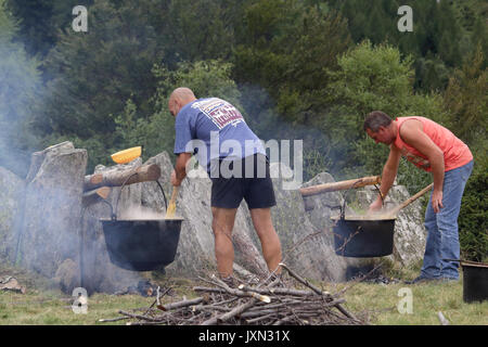 La semoule de polenta italienne (bouillie) par cuisson lente sur la flamme dans un chaudron sur un feu de charbon de bois et au cours d'un repas rural dans une forêt Banque D'Images