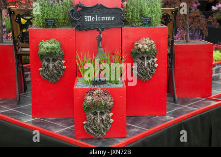 Jardinières rouges, panneau de bienvenue, conteneurs végétaux à Southport, Merseyside, Royaume-Uni.2017. Porte-pot de plantes de visage Greenman Decorative Garden Myth Sculpture planter expositions qui ont pour but d'impressionner les visiteurs de ce célèbre événement annuel. Banque D'Images