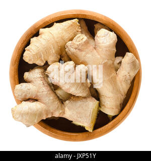 Les racines de gingembre dans un bol en bois. Les rhizomes frais de Zingiber officinale, utilisé comme épice ou une médecine populaire. Macro photo alimentaire isolé près du dessus. Banque D'Images