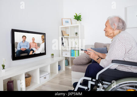 Grand-mère sur fauteuil roulant Regarder la vidéo à la télévision à la maison Banque D'Images