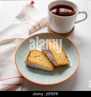 Tasse de thé et deux tranches de gâteau dans une assiette sur un tableau blanc avec un torchon blanc et rouge. Vue d'en haut. Format carré. Banque D'Images