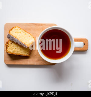 Tasse de thé et deux tranches de gâteau sur une planche à découper en bois. Vue d'en haut. Format carré. Banque D'Images