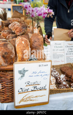 Paniers de pain frais pour la vente sur l'affichage à un marché de producteurs. Baguettes et pain d'olive rustique. Emplacement : Oakland, Californie Banque D'Images