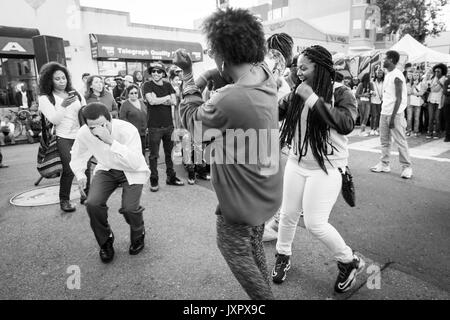 OAKLAND, CA - Aug 6, 2014 : Les gens danser dans la rue au cours de l'Art Galerie hop mensuel murmure. Foule diversifiée d'artistes et les gens branchés. Monochrome. Banque D'Images