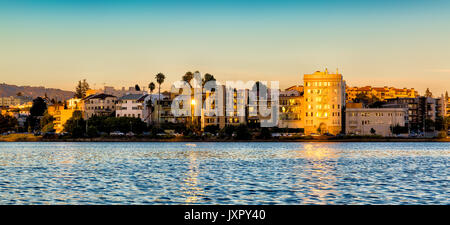 Oakland, Californie Lake Merritt waterfront buildings lit jusqu'au coucher du soleil. Vue depuis l'eau. Banque D'Images