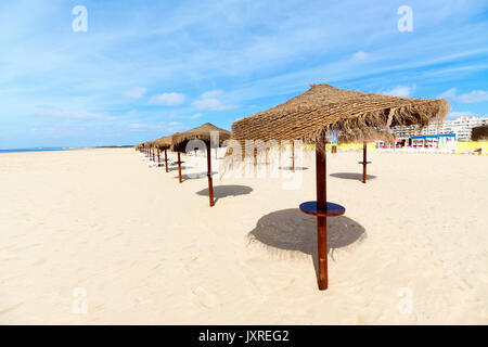 Ligne de parasols sur la plage de Monte Gordo dans la province de l'Algarve, Portugal sur une journée ensoleillée avec des nuages dans le ciel bleu. Banque D'Images