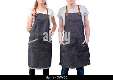 Jeunes chefs ou maîtres d'homme et de la femme pose, portant des tabliers isolé sur fond blanc. Café café barista uniforme. Banque D'Images