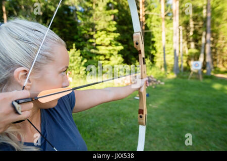 Femme Archer visant la flèche sur la carte cible à Forest Banque D'Images