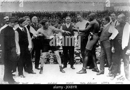 Les boxeurs Stanley Ketchel (au centre à gauche) et Jack Johnson (au centre à droite) se tiennent sur le ring avant leur célèbre match, avec l'arbitre de boxe de Californie Jack Welsh (au centre) entre les deux boxeurs, entourés d'autres membres de l'industrie, à Colma, en Californie, en 1909. Banque D'Images