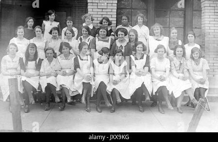 Portrait complet d'un groupe de filles d'école, première rangée assise, deuxième et troisième rangées debout, toutes les filles portant des uniformes, des expressions souriantes; une fille noire dans la troisième rangée, expression faciale neutre; Bridgeport, Ohio, 1920. Banque D'Images