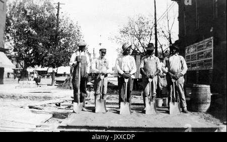 Coup de quatre garçons afro-américains, posant de la même façon avec des pelles devant leurs jambes, à l'extérieur; Liban, Pennsylvanie, 1920. Banque D'Images