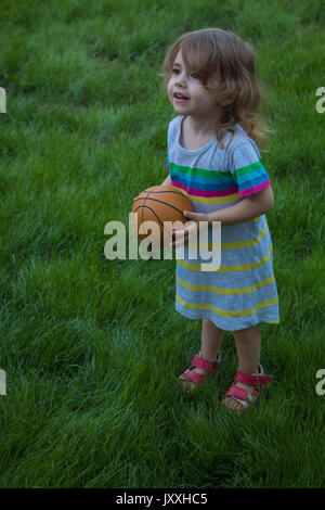 Petite fille jouer avec la balle dans le parc Banque D'Images