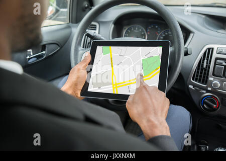 Close-up of Businessman Sitting in Car en utilisant le système de navigation GPS sur tablette numérique Banque D'Images