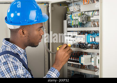 Close-up of young male Technician l'examen de la boîte à fusibles avec tournevis Banque D'Images