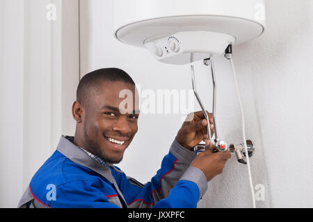 Smiling Young Woman Plumber Repairing Chaudière électrique Banque D'Images