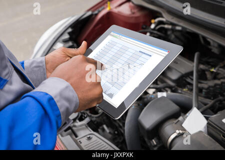 Close-up of Mechanic With Digital Tablet graphique tout en montrant l'examen de voiture Banque D'Images