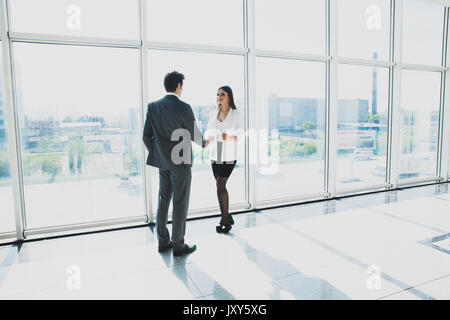 Vue de dessous de deux jeunes hommes d'affaires sont debout dans un bureau moderne, doté de fenêtres panoramiques. Banque D'Images