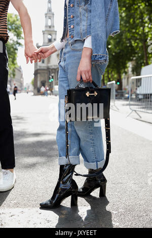 Femme en denim avec sac à main tenant la main de l'homme, low section Banque D'Images