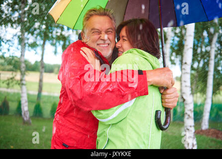 Couple standing et embrancing under umbrella Banque D'Images