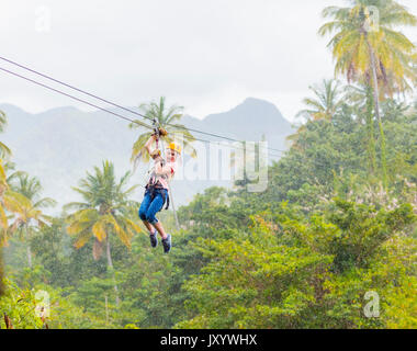 Caucasian girl hanging on zip line in forest Banque D'Images