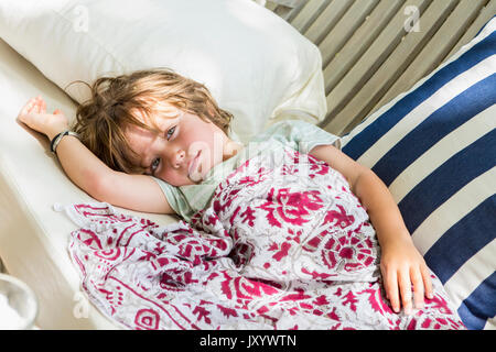 Young boy portant sur une chaise Banque D'Images