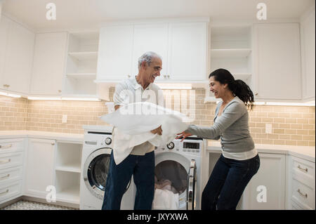 Playful couple serviette pliage dans buanderie moderne Banque D'Images