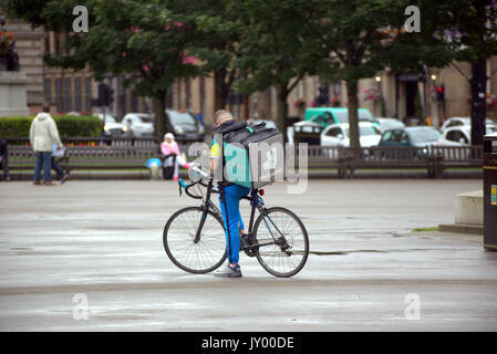 Wet George square Glasgow garçon jeune homme Deliveroo cycliste vélo livraison livraison alimentaire sms en attente de travail en ce qui concerne la prestation de l'extérieur, sur la route de rue Banque D'Images