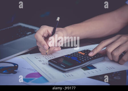 Close up business man hand holding smartphone et faire financer et de calculer le coût d'une table en bois au bureau à domicile. concept comptable. Banque D'Images