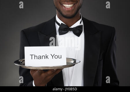 Close-up of an African Waiter Holding Carte de remerciement dans le bac Banque D'Images